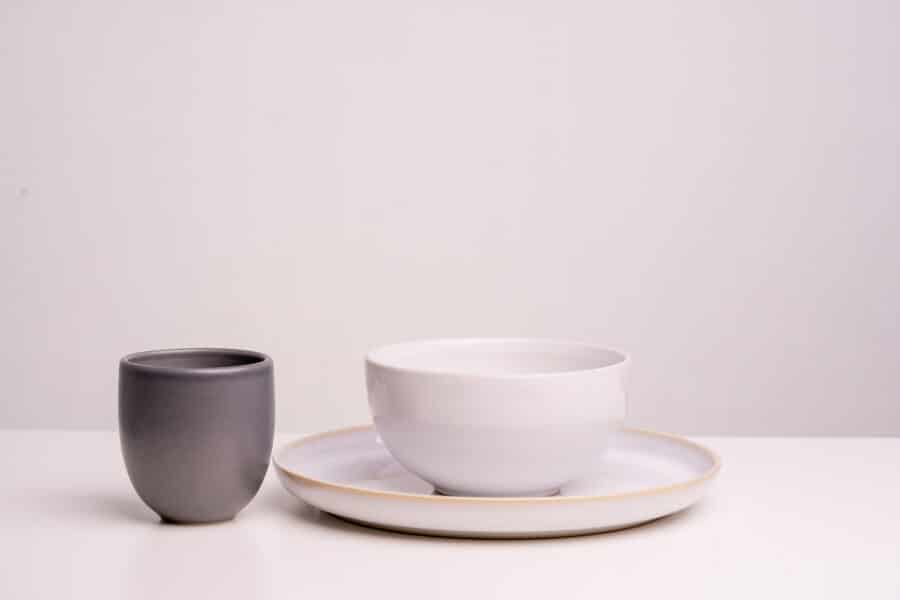 schwarze Tasse, weißer großer Teller, weiße Bowl