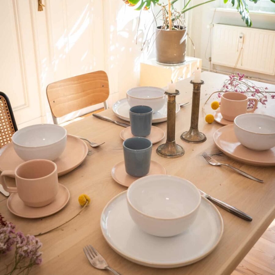 Großes handgemactes Geschirr set für 4 Personen gedeckt auf einem Tisch im Wohnzimmer für die Familie