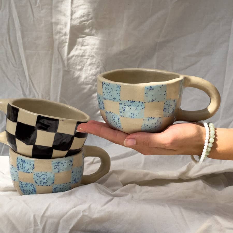 Tassen Set aus handgetöpferten Keramik Tassen in schwarz und blau kariert vor einem weißen Laken