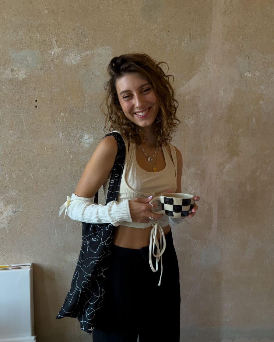 Rebecca mit der handgetöpferten schwarz karierten Tasse vor einer Wand im minimalistischen Look