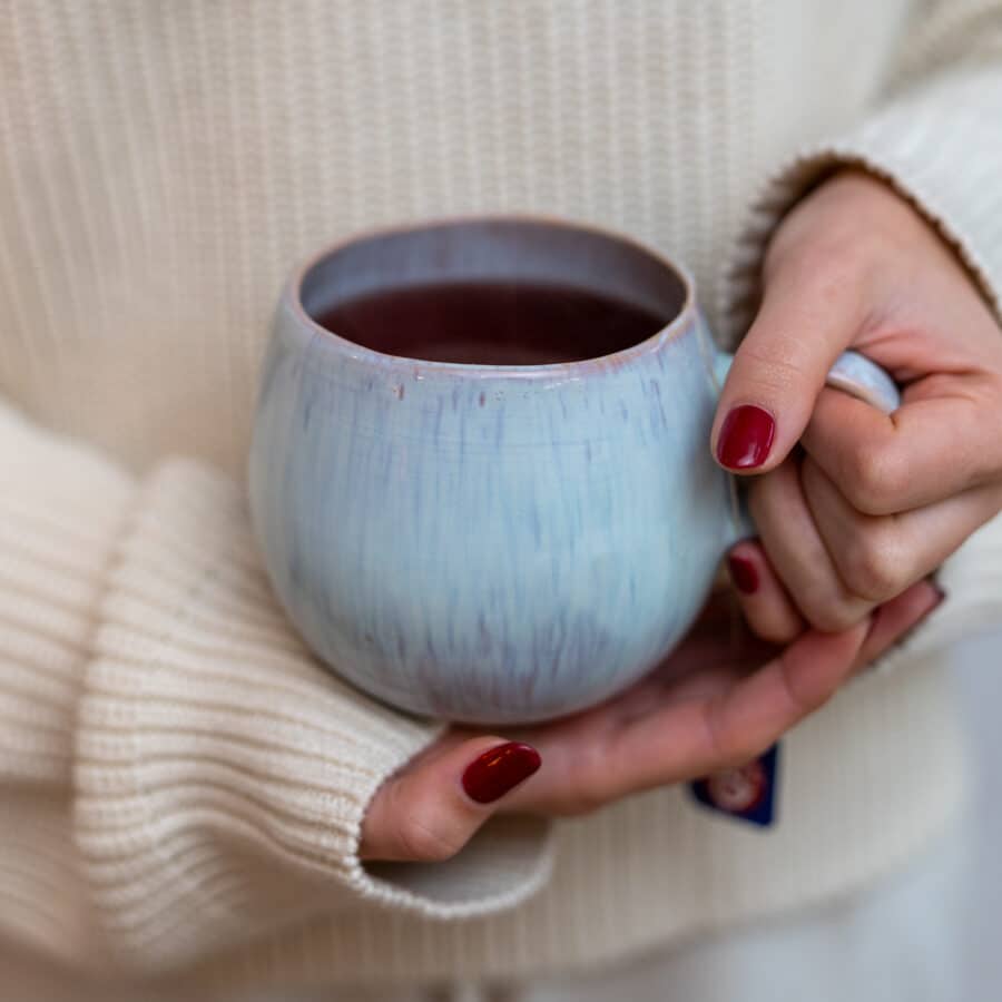 Faro Teetasse aus Teingut in der Hand einer Frau gefüllt mit Tee