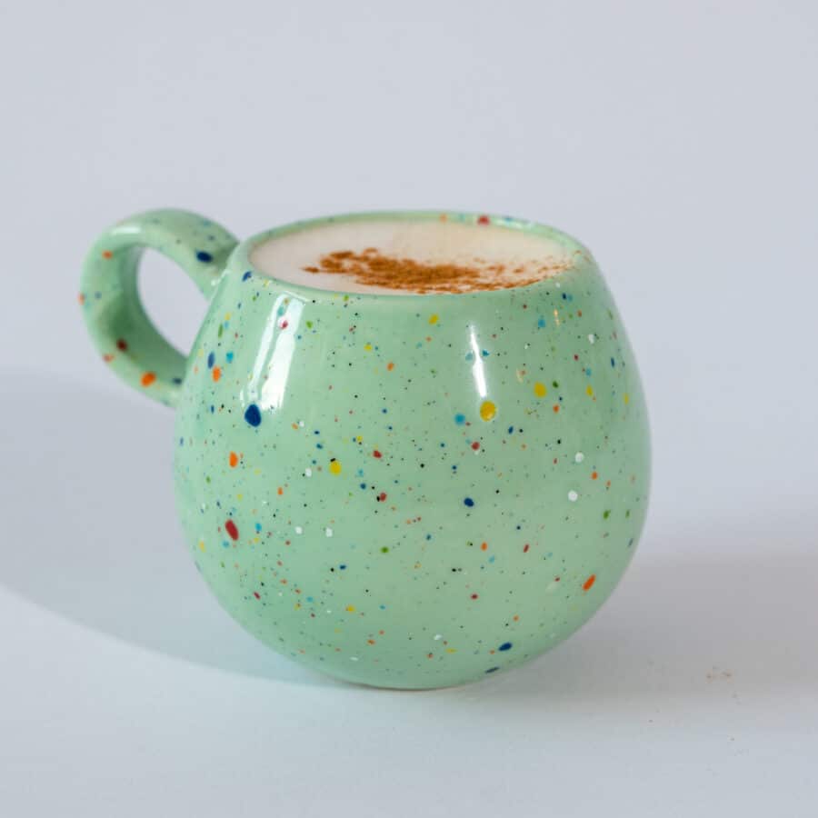 Bauchige Steingut Tasse gefüllt mit Cappuccino auf hellem Untergrund